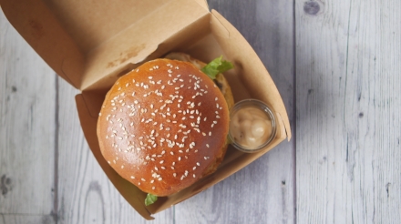 beef burger and french fries in a takeaway paper box on table